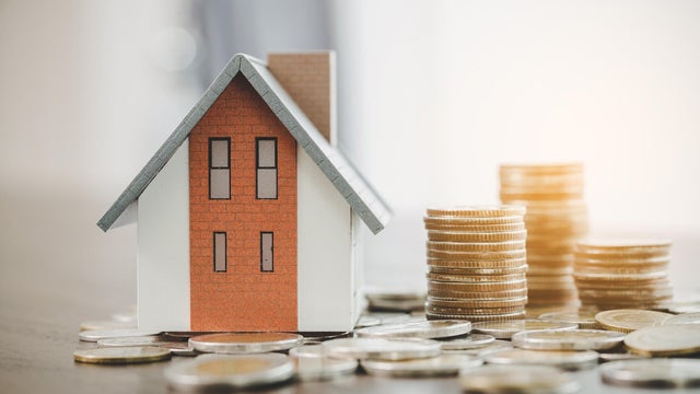 House model and money coins stacks on blur table background. Savings plans for home, loan, investment, mortgage, finance and banking about house concept. 