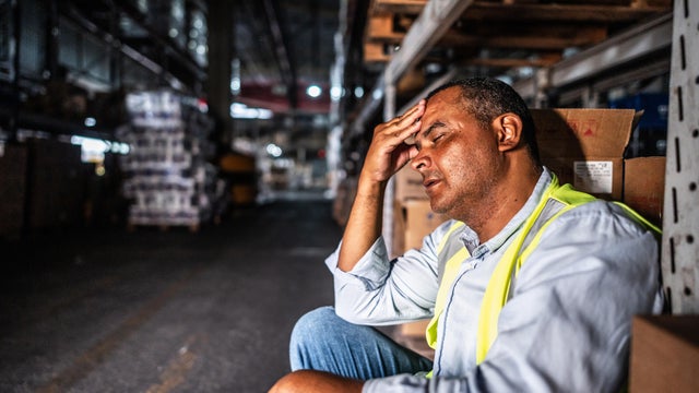 Tired mature man sitting at work in a warehouse 
